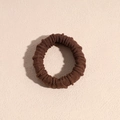 Dettaglio dell'elastico per capelli in tessuto a coste marrone su sfondo beige - caffè