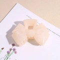 Detail of elegant cream apricot acrylic bow hair claw clip showing smooth resin texture - Off White