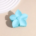 Gros plan d'une pince à cheveux fleur bleu ciel mat sur fond texturé beige - Bleu