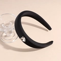 Close-up of black satin padded headband featuring a sparkling crystal heart embellishment - Black