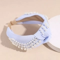 Dettaglio di un cerchietto annodato azzurro con più file di perle bianche e tessuto - Blu