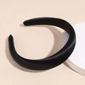 Detalle de una diadema ancha de satén negro con relleno grueso sobre un soporte blanco - Negro