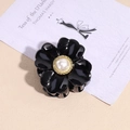 Détail d'une pince à cheveux fleur noire brillante avec une perle centrale et bordure dorée - Noir