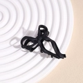 Detail view of the matte black bow hair claw clip on a minimalist textured plate - Black Bow