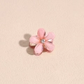 Makroaufnahme einer kleinen rosa Kamelien-Haarklammer mit Goldglitzer und einem Strassstein - Hellrosa