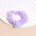 Gros plan d'un chouchou violet clair avec perles colorées sur support blanc - Violet