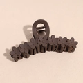 Dettaglio macro di un mollettone per capelli marrone opaco con piccoli elementi floreali - Marrone