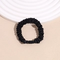Primer plano de coletero de satén plisado negro en elegante soporte de exhibición blanco - Negro