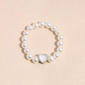 Detailed macro view of an elastic faux pearl bracelet with a gold-rimmed heart charm - Transparent Heart Pearl Hair Tie