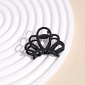 Close-up of small matte black claw clip with crown shape design on textured background - Crown Black