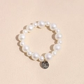 Detail of elegant pearl hair tie with vintage silver relief pendant on a beige surface - Textured Pearl Hair Tie Bracelet