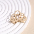 Matte beige crown-shaped hair claw clip with hollow design on a round display tray - Crown Khaki
