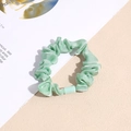 Detailed macro view of mint green satin scrunchie with shiny texture and smooth resin buckle - Green