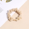 Detail of a champagne satin scrunchie with smooth pleated texture and decorative resin buckle - Champagne