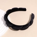 Detail of a black twisted velvet headband with glossy texture on a beige background - Black