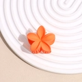 Détail macro d'une petite pince à cheveux fleur orange sur un plateau blanc texturé - Orange