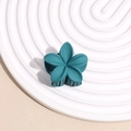 Gros plan d'une pince à cheveux fleur bleu foncé mat sur un fond texturé élégant - Aqua