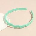 Detail view of mint green wavy headband with anti-slip teeth on a textured surface - Mint Green