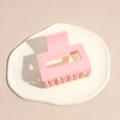 Primer plano de una pinza para el cabello cuadrada rosa mate en soporte minimalista - Rosa
