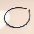 Detail view of dark blue wavy headband with anti-slip inner teeth on beige texture - Navy Blue