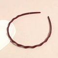 Detail of burgundy wavy headband with inner teeth for secure grip on beige surface - Burgundy