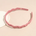Detalle de diadema ondulada rosa mate con dientes antideslizantes internos en fondo beige - Rosa