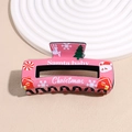 Detail of pink Christmas hair claw clip featuring Santa Baby print and festive patterns - Pink