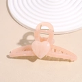 Close-up of a pink heart-shaped acetate claw clip with marble texture on display - Pink