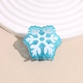 Détail d'une pince à cheveux bleue transparente avec paillettes argentées et flocons blancs - Flocon de neige