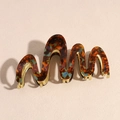 Close-up of wavy tortoiseshell acetate hair claw clip with golden metal inner teeth - Amber
