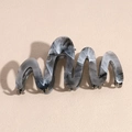 Detail of a wavy acetate shark hair clip with a stylish black and white marble pattern - Gray