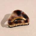 Macro detail of tortoiseshell acetate hair claw clip with golden metal teeth - Amber