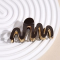Close-up of wavy brown acetate hair claw clip with golden metal teeth and spring mechanism - Brown