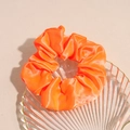 Detail view of bright orange LED satin scrunchie resting on a stylish glass tray - Orange