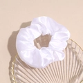 Dettaglio macro di elastico per capelli in raso bianco su un vassoio di vetro - Bianco