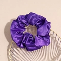 Dettaglio di un elastico per capelli in raso viola scuro con trama setosa in vassoio - Viola