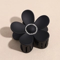 Dettaglio di una molletta per capelli a fiore nero opaco con strass argentati brillanti - Nero