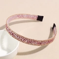 Detail van roze glitter haarband met gouden kettingrand rustend op witte keramiek - Roze