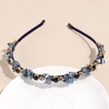 Macro shot of blue crystal hairband with gold settings on a decorative white dish - Navy Blue
