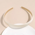 Dettaglio del cerchietto in raso crema appoggiato su un piatto di ceramica bianca opaca - Beige