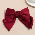 Detail einer eleganten weinroten Satin-Haarschleife mit glatter und glänzender Textur - Roter Federclip