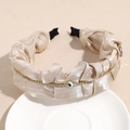 Détail d'un serre-tête en satin champagne avec chaîne en strass et cristal central scintillant - Champagne