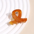 Dettaglio del fermaglio per capelli in acetato tartarugato con design a incrocio - Arancione