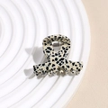 Dettaglio ravvicinato di una piccola molletta per capelli in acetato con motivo a pois - Pois Nero Beige