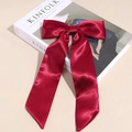 Dettaglio dell'elegante fiocco per capelli in raso rosso vino con nastri su un libro - Rosso