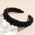 Dettaglio di un cerchietto nero con perle di varie dimensioni su una tazza bianca - Nero
