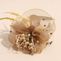 Dettaglio di un fascinator vintage con velina a rete, perle sintetiche e decorazioni floreali - Champagne