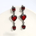 Macro shot of dark gothic heart earrings with red faceted stones on a display stand - Triple Layered Red Hearts Style / 3 Hearts