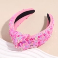 Detailansicht eines rosa Haarreifs mit glitzernden Pailletten und modernem Knotendesign - Rosa