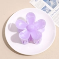 Detail view of a translucent purple flower hair claw clip on a white ceramic plate - Purple